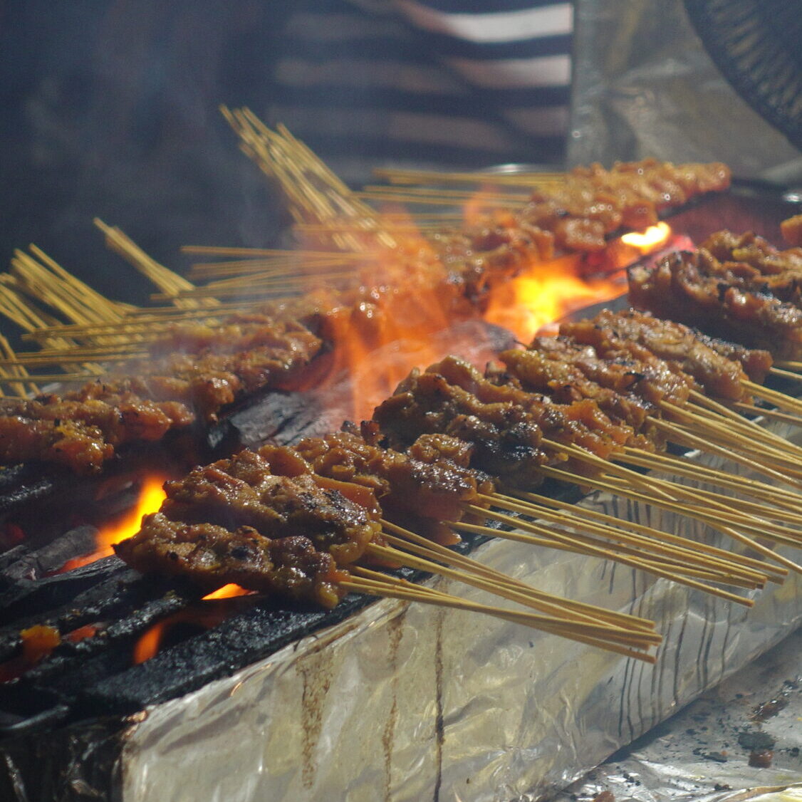 Close-up of satay skewers grilling at Lau Pa Sat night market