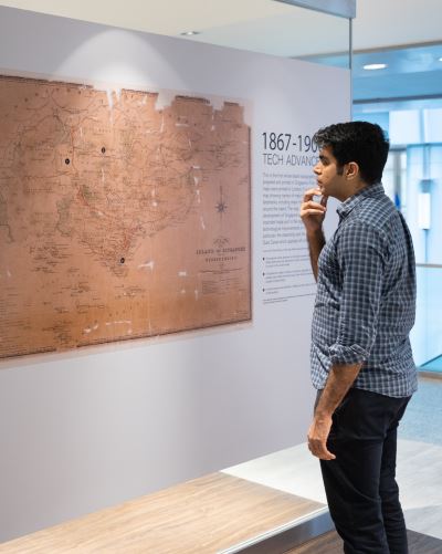 Visitor examining a detailed historical map at Singapore City Gallery, showcasing Singapore's growth and development from 1867 to 1990.