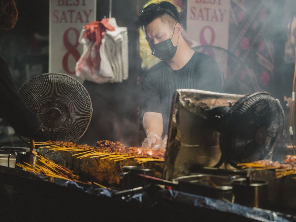 Grilling satay skewers at night market in Lau Pa Sat, Singapore