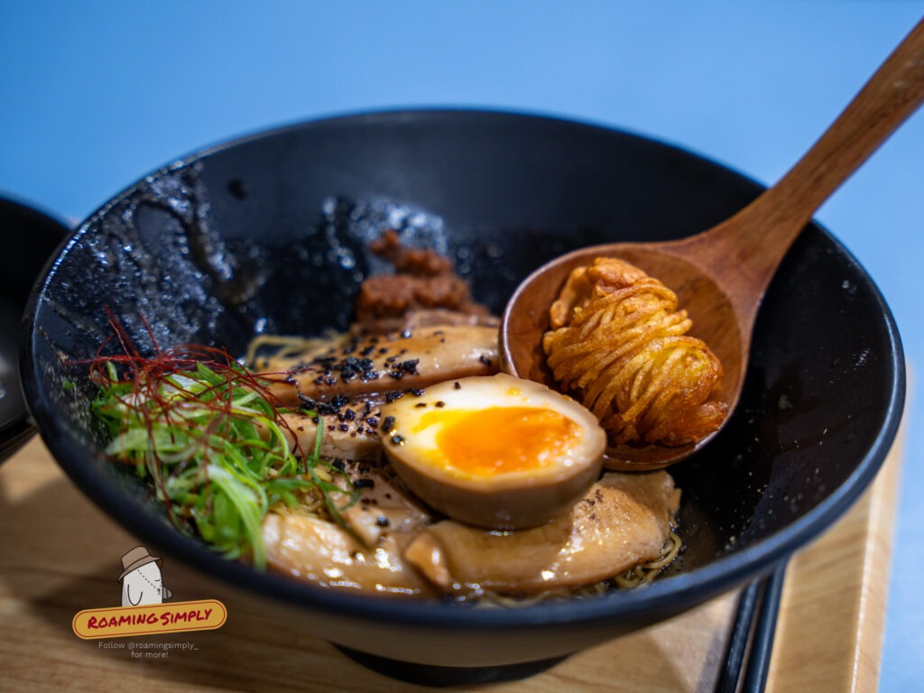 Authentic Japanese ramen with marinated egg and side dishes served at a Singapore restaurant, RoamingSimply travel guide.
