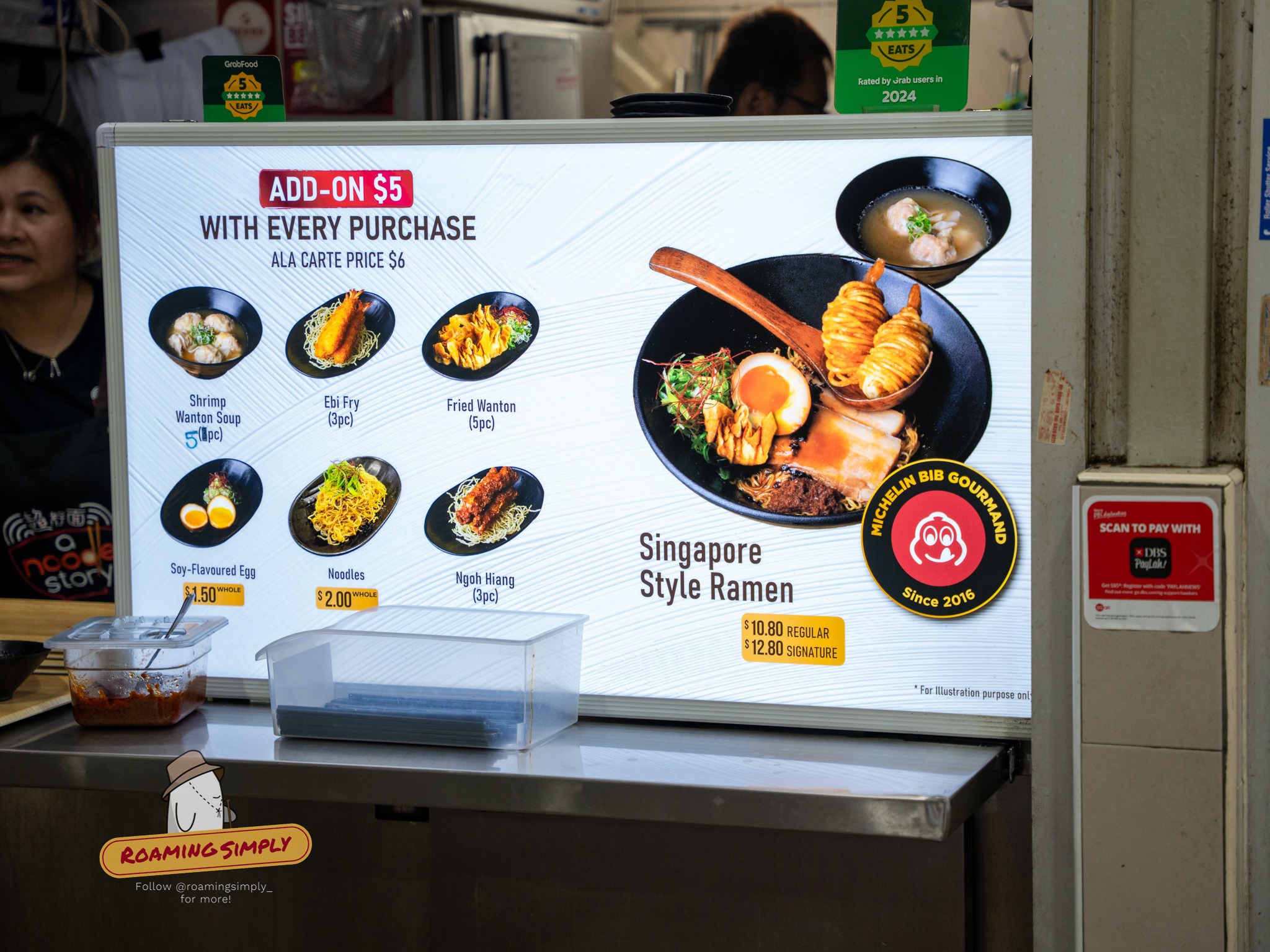 A Noodle Story menu board at Amoy Street Food Centre showing Singapore style ramen and add-on sides.