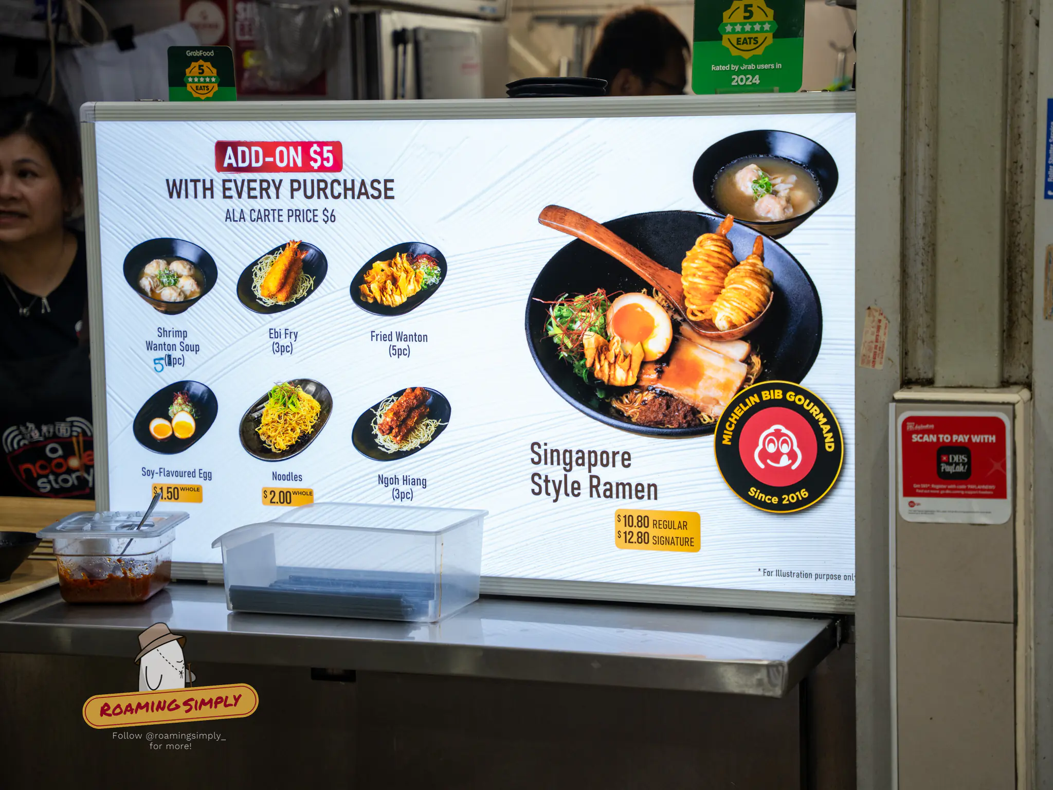 A Noodle Story menu board at Amoy Street Food Centre showing Singapore style ramen and add-on sides.
