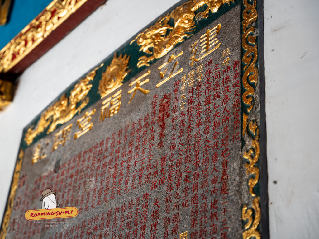Angled close-up of a stone tablet at Thian Hock Keng Temple featuring engraved Chinese calligraphy in gold and red, listing historical donations from early immigrants.