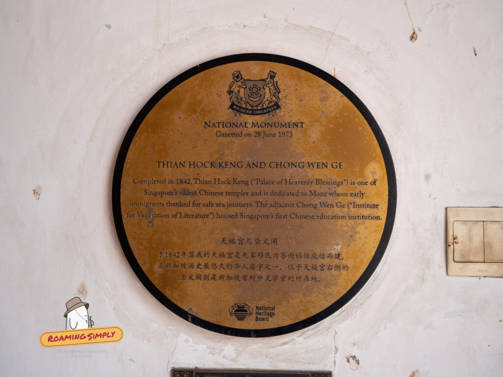 Circular gold National Monument plaque on a white wall, designating Thian Hock Keng and Chong Wen Ge as a gazetted monument on 28 June 1973. The text describes the temple's dedication to Mazu and the school's history.