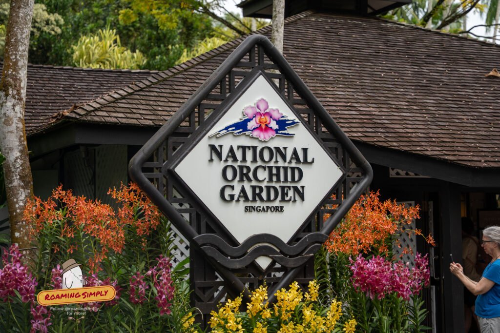 Entrance sign of the National Orchid Garden, Singapore, framed by orange, pink and yellow orchids